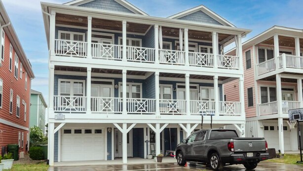 A two-story residential building with a balcony on each floor, a garage, and a driveway. - Well equipped 5 bedroom home near Fort Fisher (Kure Beach)