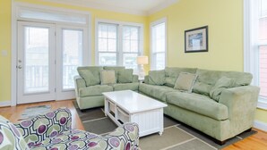 A living room with a sectional sofa, a white coffee table, patterned armchairs, and a framed picture on the wall. - Well equipped 5 bedroom home near Fort Fisher (Kure Beach)