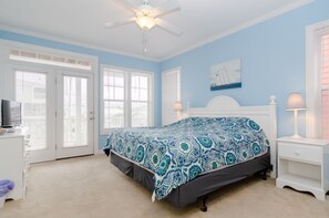 Ein Schlafzimmer mit einem Bett, einem Deckenventilator, einem Schminktisch und einem Nachttisch.