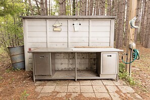 A metal utility shed with a workbench, a fish hanging on the wall, and a hose attached to the side.