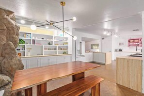 Una cucina moderna con mobili bianchi, un tavolo da pranzo in legno e un'originale parete rocciosa.