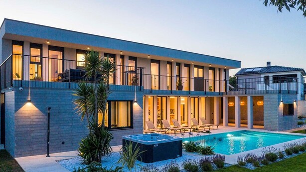 Uma casa moderna de dois andares com piscina, área de estar externa e ofurô.