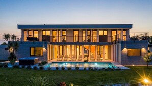 Uma casa moderna de dois andares com piscina, janelas amplas e um gramado bem cuidado.