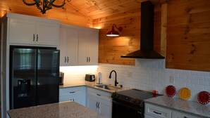 A kitchen with white cabinets, a black refrigerator, a stove, and a sink.