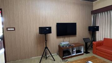 Een woonkamer met een flatscreen televisie, twee staande speakers, een houten salontafel en een rode bank.