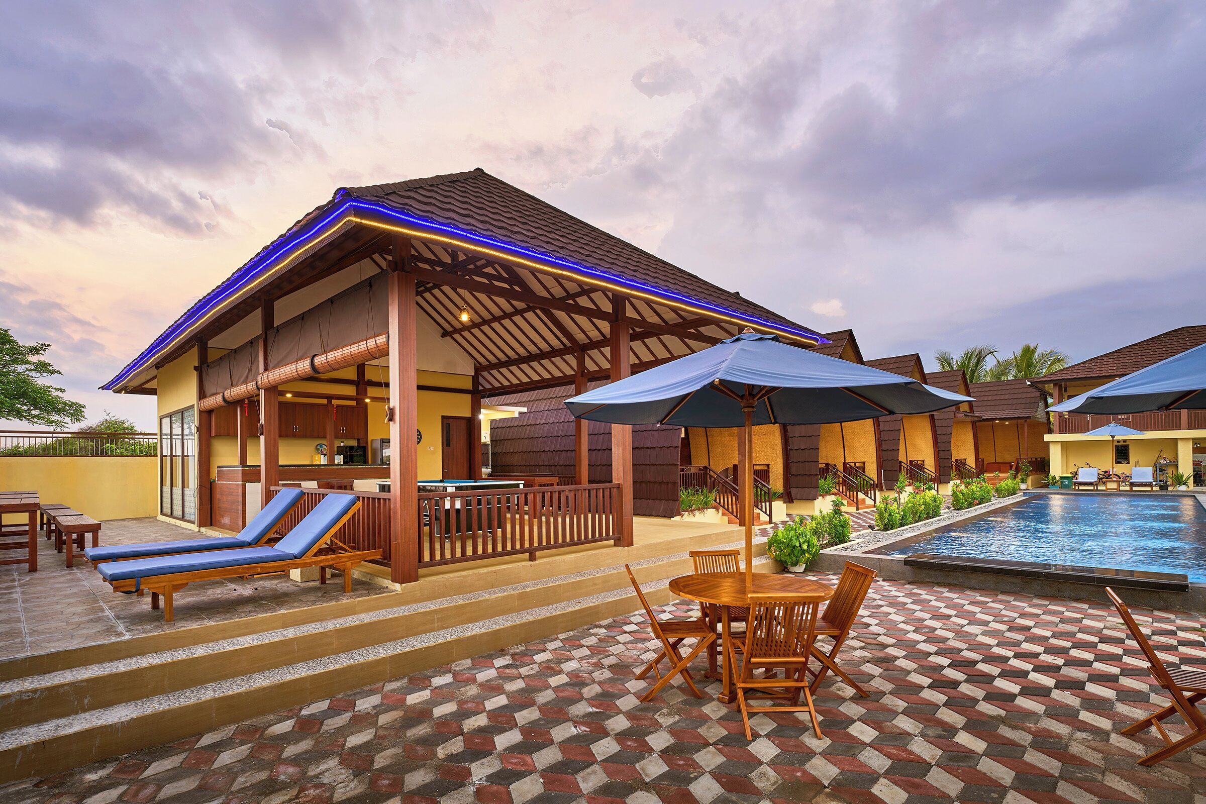 A resort with a swimming pool, lounge chairs, and a covered patio area.