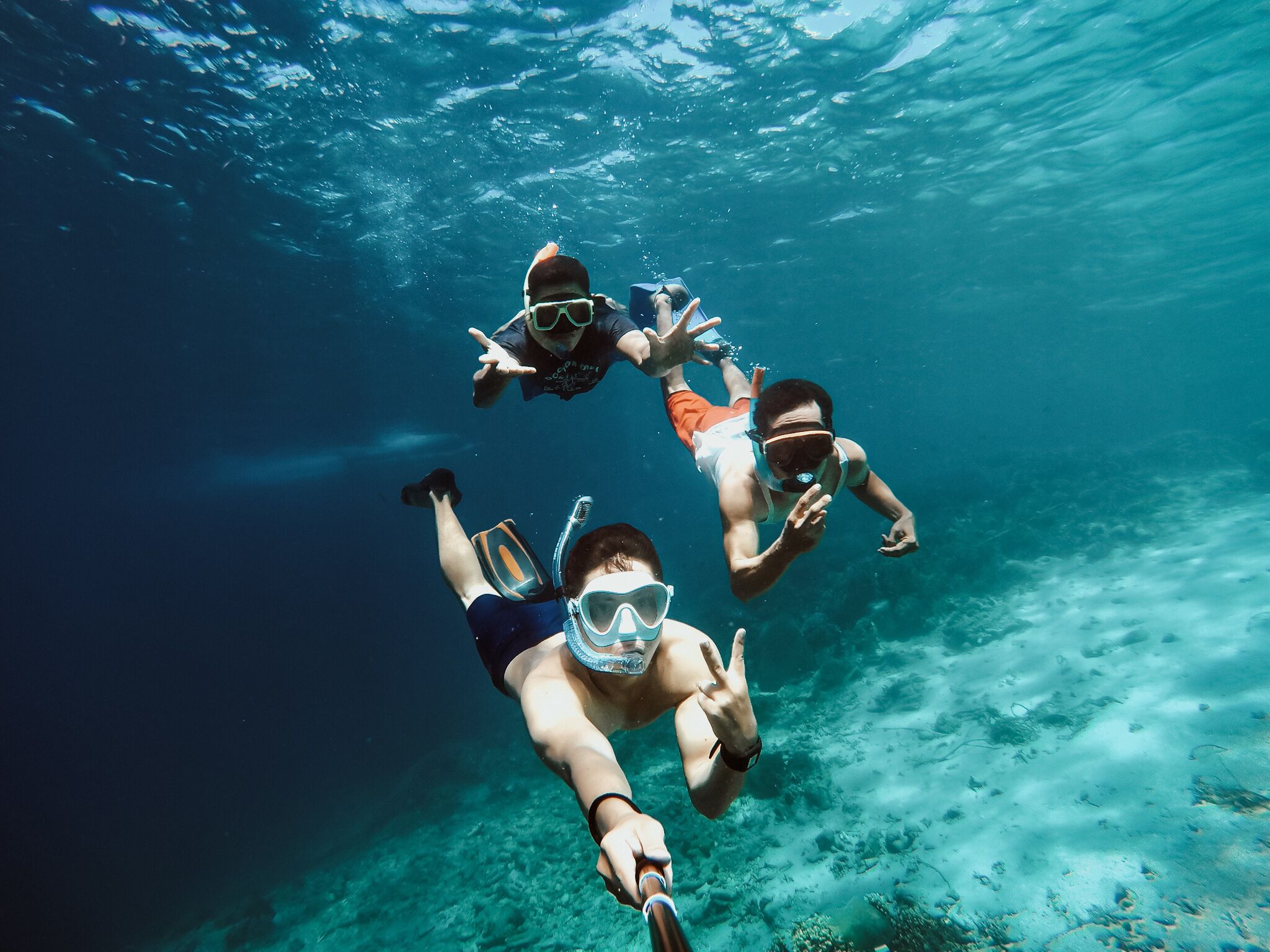 Trois personnes font de la plongée avec tuba.