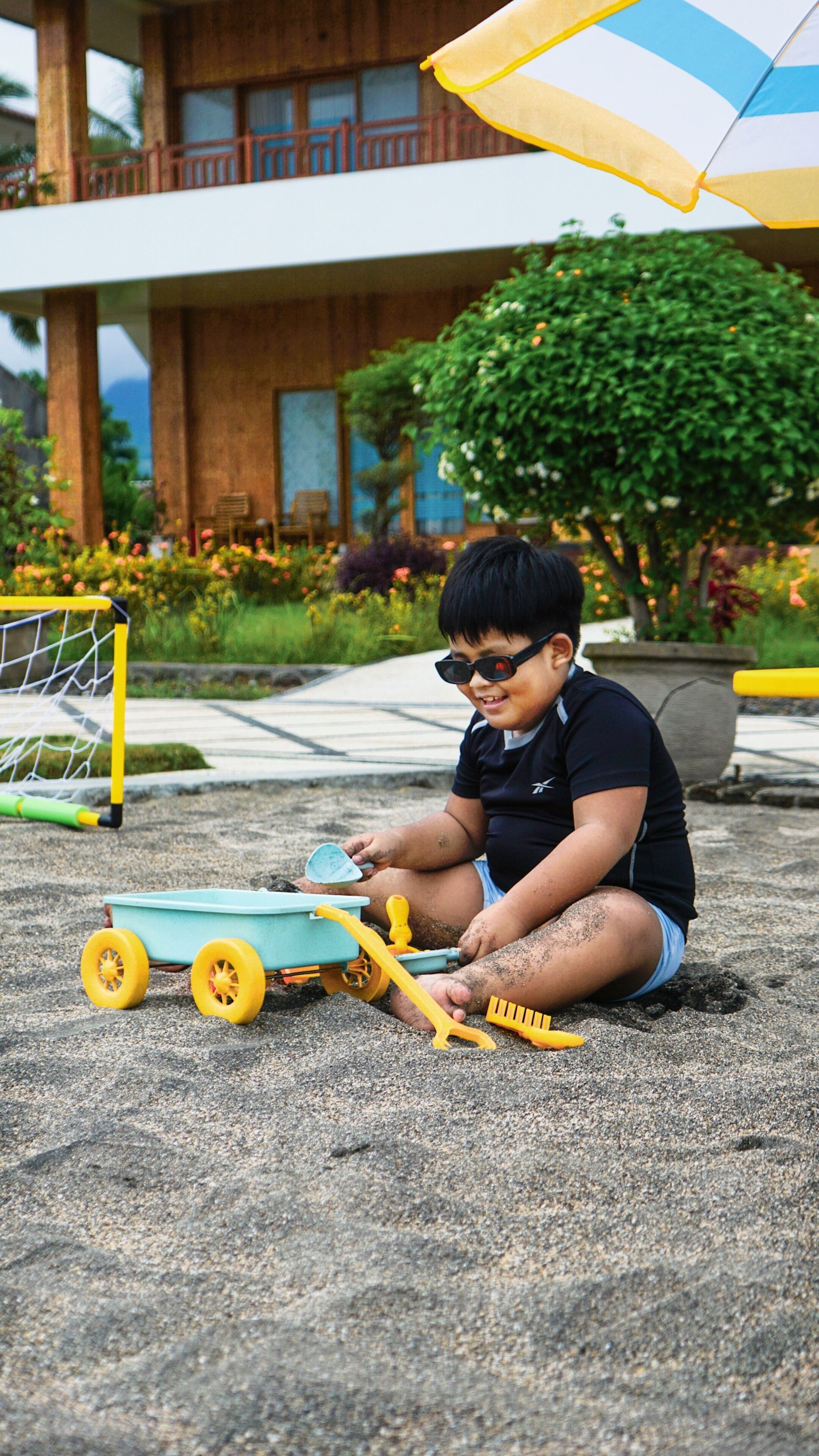 A child playing with a toy vehicle on a paved surface.