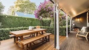 A wooden deck with a picnic table and benches, surrounded by a hedge and flowering plants. - 'Blooms At Berry' - Luxury in the Heart of Berry (Berry)