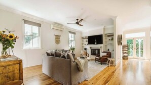A spacious living room with a sofa, a fireplace, and a TV. - 'Blooms At Berry' - Luxury in the Heart of Berry (Berry)