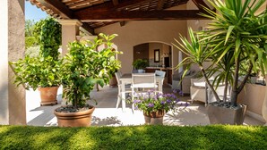 Eine Außenpatio mit einer Holzpergola, Blumentöpfen und einer Essbereich mit Stühlen und einem Tisch.