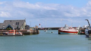 Un port où sont amarrés des bateaux, un phare et un bâtiment doté d’un toit en pente.