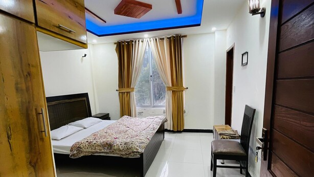 A bedroom with a bed, a chair, a wardrobe, and a window with curtains. - Paradise View Hotel And Restaurant (Khaira Gali)