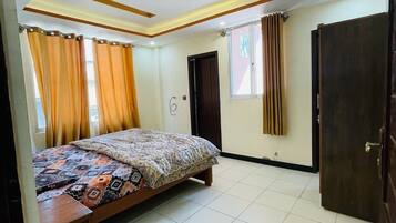 Quarto com cama, cortinas, porta e janela.