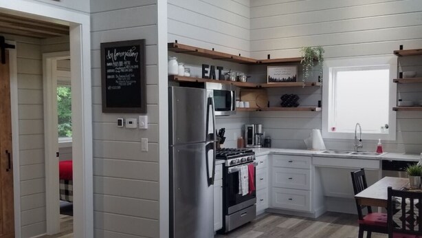 A modern kitchen with white cabinets, stainless steel appliances, and wooden shelves. - Vacation home you’ll enjoy (Lower Sackville)