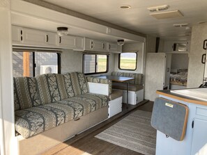 Cozy living area with a sofa, dining table, and kitchenette, offering a functional space with views of the outdoors.