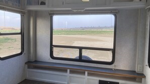 A train car interior with a bench and large windows offering a view of the countryside. - Camper/RV @ The Rendezvous - Wi-Fi, fire pit, A/C (Cody)