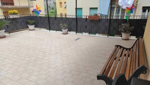 Une terrasse carrelée avec un banc en bois et des plantes en pot.