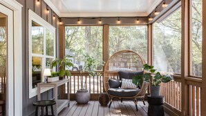 A sunroom with a wicker chair, a small table, and potted plants.