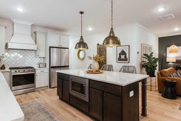 A modern kitchen with stainless steel appliances, a large island, and pendant lighting. - Newly built home in Five Points — 1 mile to UGA (Athens)