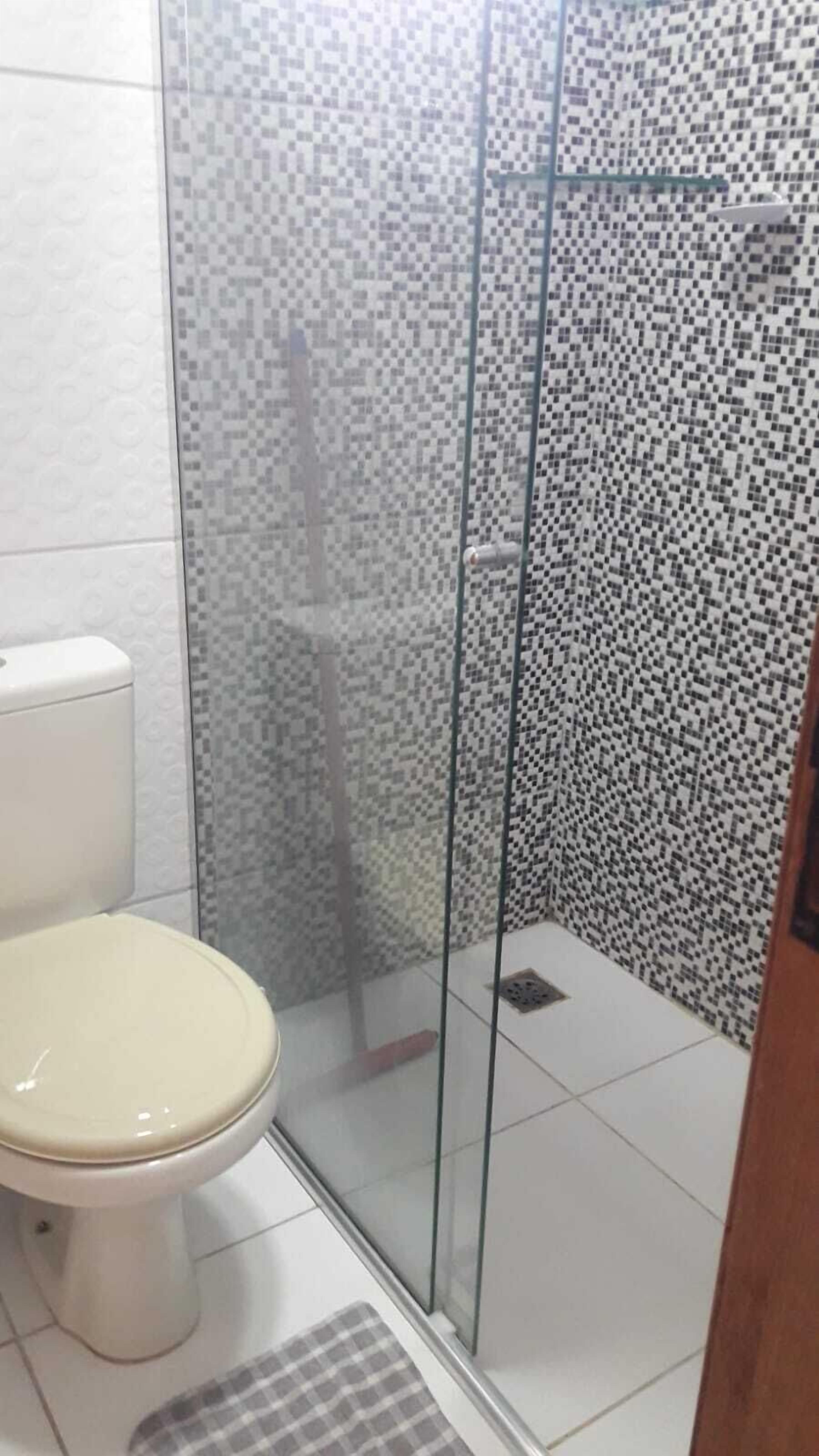 Ein Badezimmer mit Toilette, einer Duschkabine aus Glas und gefliesten Wänden.