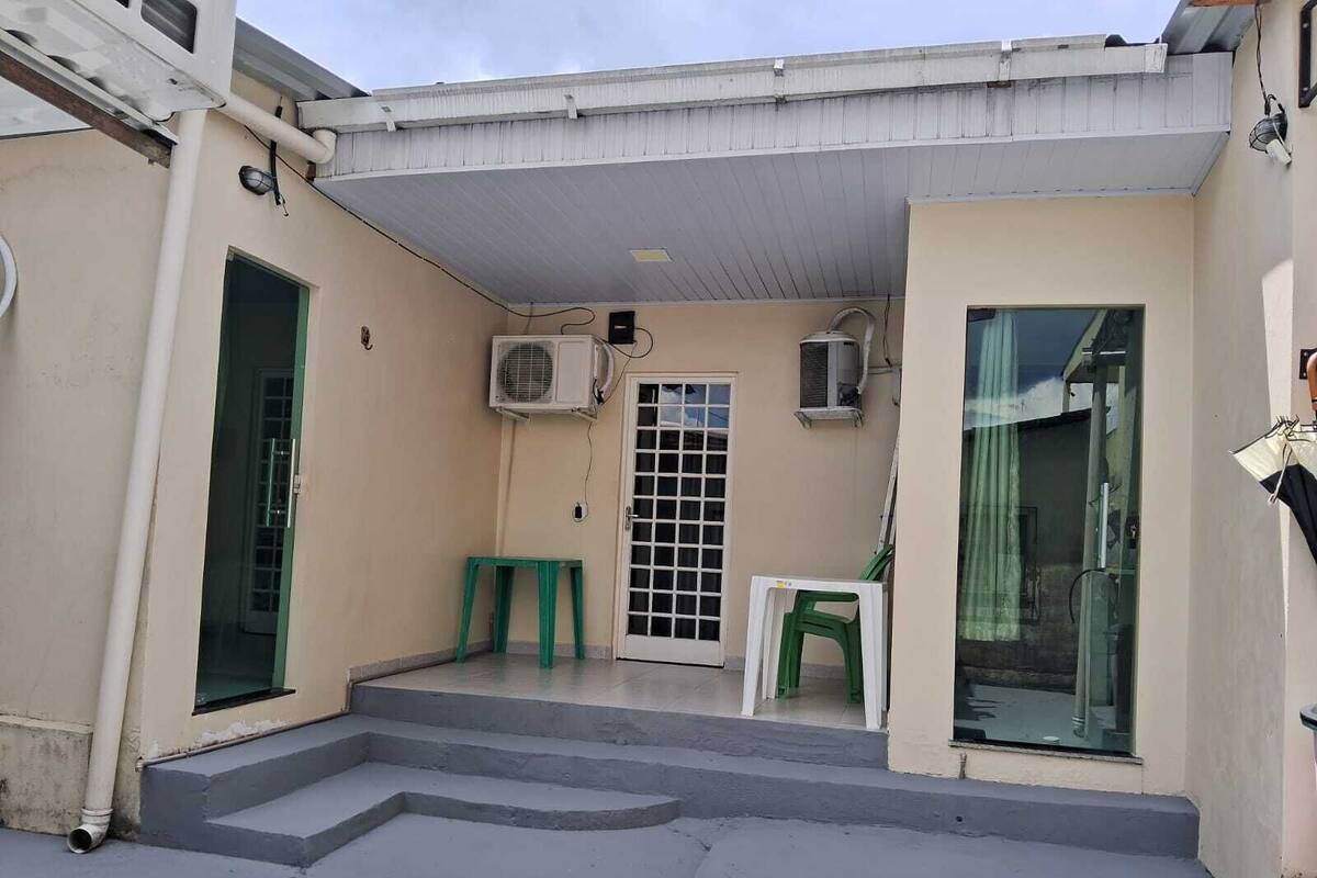 A covered outdoor area with a concrete staircase leading to a door, two air conditioning units, and a small table.