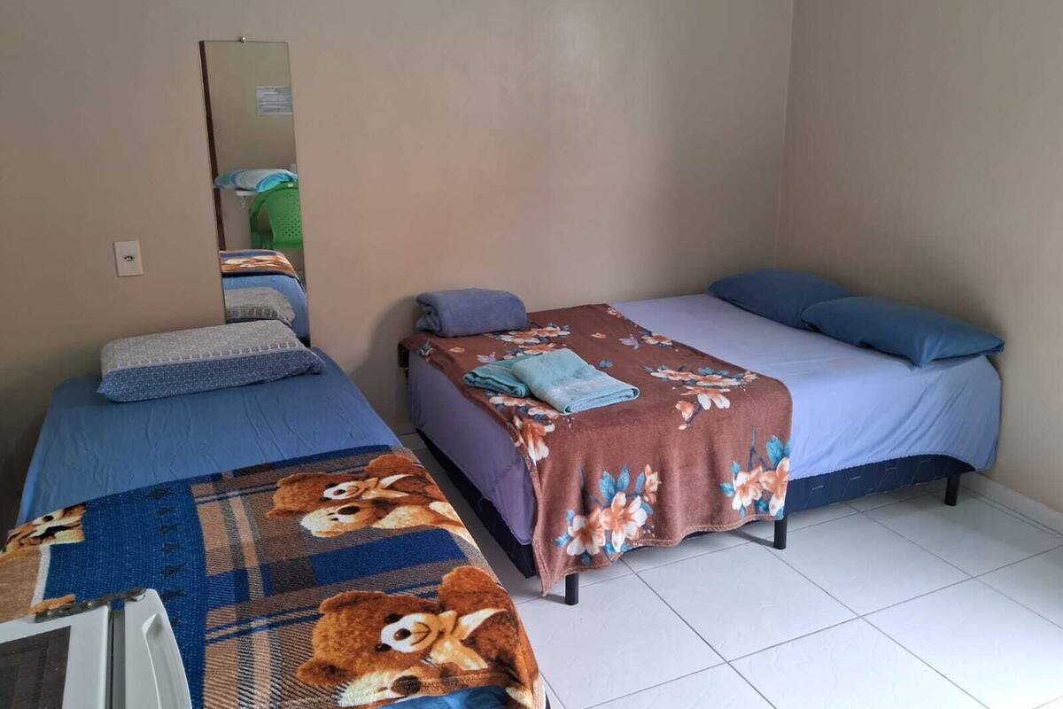 A room with two single beds, each with a blue and a floral-patterned bedspread, and a small table with a mirror.
