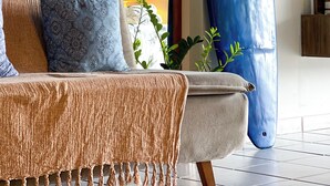 Una habitación con un sofá, un espejo grande y una tabla de surf apoyada en la pared.