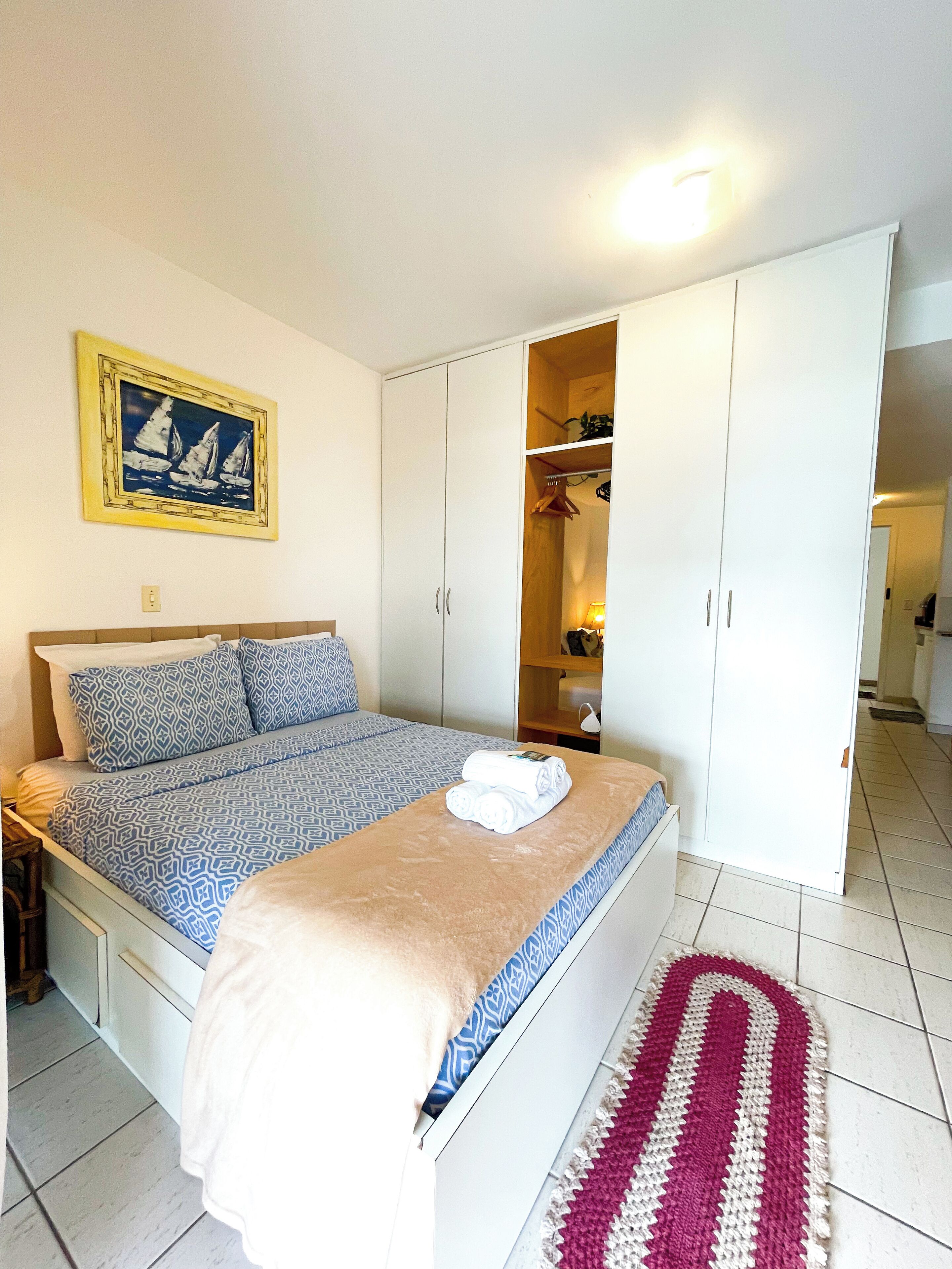 Un dormitorio con cama, armario y un cuadro en la pared.