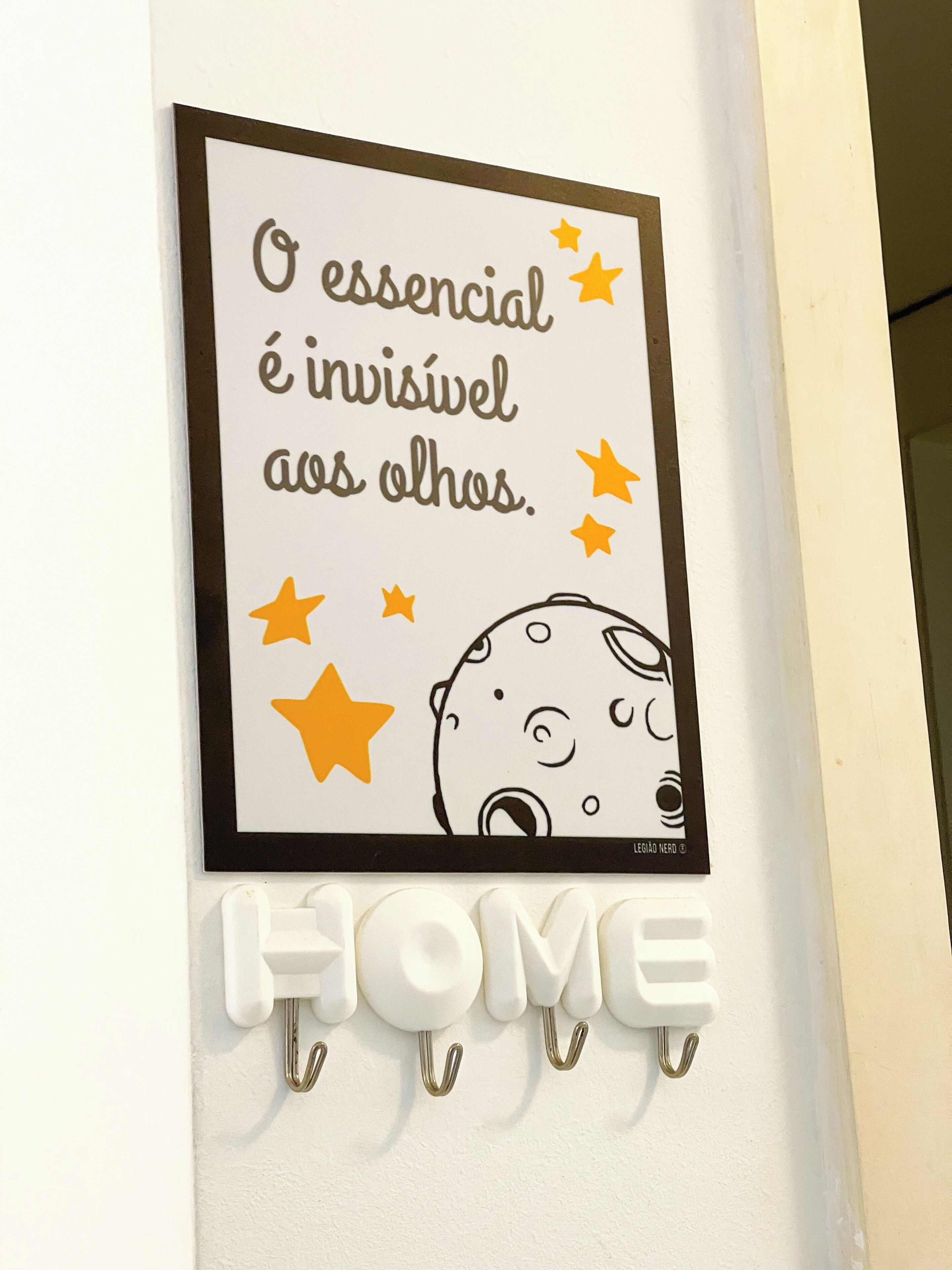 A wall-mounted sign with a quote and a cartoon character, below which is a 'HOME' sign with hooks.
