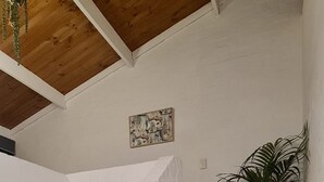 Puinen portaikko, jonka vieressä on valkoisista tiilistä muurattu seinä ja jonka yläpuolella roikkuu amppeli.