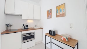 A compact kitchen with white cabinets, a built-in oven, a coffee maker, and a small table with a mug. - N&J - STUDIO RIVIERA - Central - Very close sea (Niza)