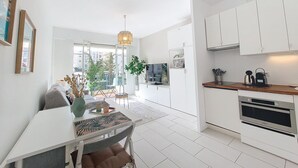 A modern kitchen with white cabinets, a built-in oven, and a dining area with a table and chairs. - N&J - STUDIO RIVIERA - Central - Very close sea (Niza)
