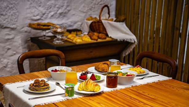 Une table de petit-déjeuner avec divers plats, notamment des crêpes, des croissants et des fruits.