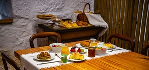 Une table de petit-déjeuner avec divers plats, notamment des crêpes, des croissants et des fruits.