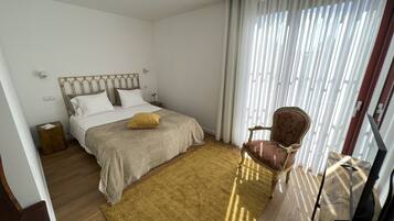 Un dormitorio con cama, una silla, una mesita y un televisor.
