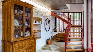 Un meuble en bois doté de portes en verre, un escalier avec des rampes rouges et un mur en pierre.