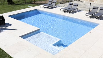 Una piscina al aire libre, sombrillas, tumbonas