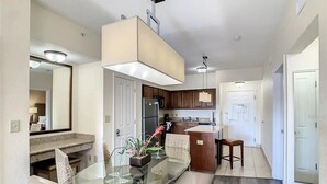 Una cocina moderna con una mesa de comedor de vidrio, armarios de madera y una isla integrada.