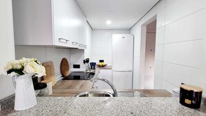 Eine moderne Küche mit weißen Schränken, einer Granit Arbeitsplatte, einer Edelstahl-Spüle und einer schwarzen Kaffeemaschine.