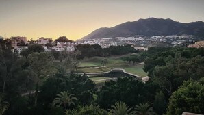 Blick auf einen Golfplatz mit einem Berg im Hintergrund und Wohngebäuden in der Umgebung.