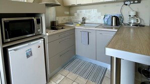 Una cocina compacta equipada con microondas, refrigerador y cafetera.