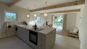 Una cocina moderna con una isla central, luces colgantes y vistas a un patio.