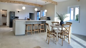 Una cocina moderna con una isla central, taburetes de madera y una mesa de comedor con sillas.