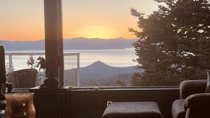 Una habitación con vista a un lago y montañas al atardecer.
