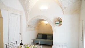 A cozy room with a dining table, chairs, a sofa, and a small white bench.