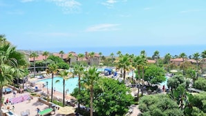A resort with a swimming pool surrounded by palm trees and lounge chairs, with a view of the ocean in the background. - Marriott’s Newport Coast - Majestic Views- 2 Bedroom - Full Resort Access (Newport Beach)
