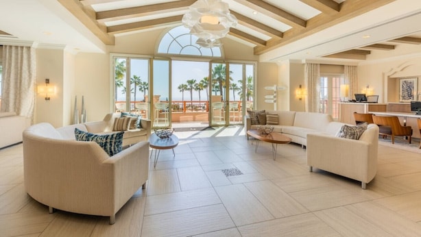 A spacious living area with a high ceiling, large windows, and a view of palm trees. - Marriott’s Newport Coast - Majestic Views- 2 Bedroom - Full Resort Access (Newport Beach)