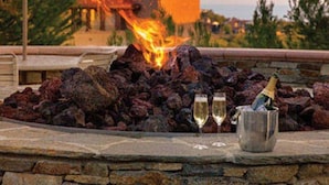 A stone fire pit with two glasses of champagne, a bottle, and an umbrella. - Marriott’s Newport Coast - Majestic Views- 2 Bedroom - Full Resort Access (Newport Beach)