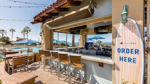 A poolside bar with a sign indicating an ordering area, overlooking a pool and palm trees. - Marriott’s Newport Coast - Majestic Views- 2 Bedroom - Full Resort Access (Newport Beach)